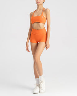 front side of women's sports bra and biker short in orange